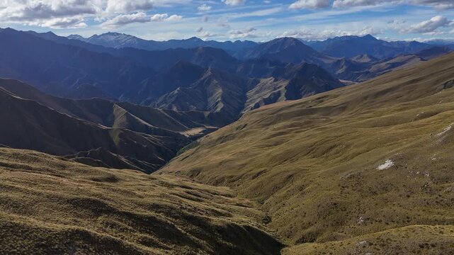 Flyover unspoiled rugged grassy mountain slopes going to the horizon