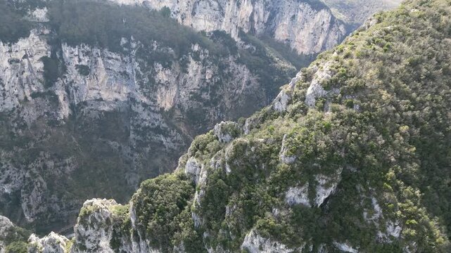 Aerial drone footage over Frasassi Gorge, Italy: rocky cliffs, green vegetation and dramatic natural landscape. Ideal for travel, nature and geological projects.
