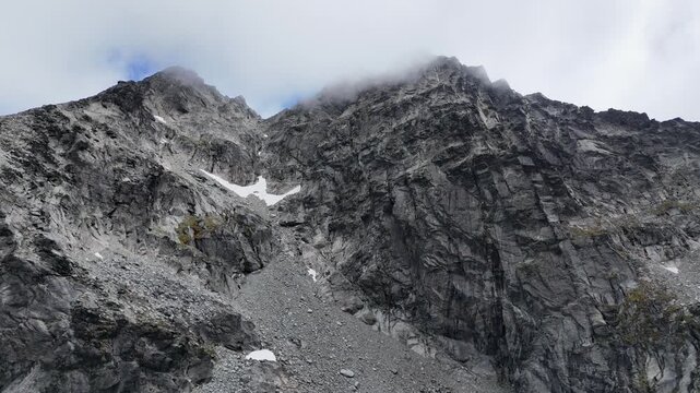 Aerial climbs up rocky mountain alpine slope, jagged and rugged nature