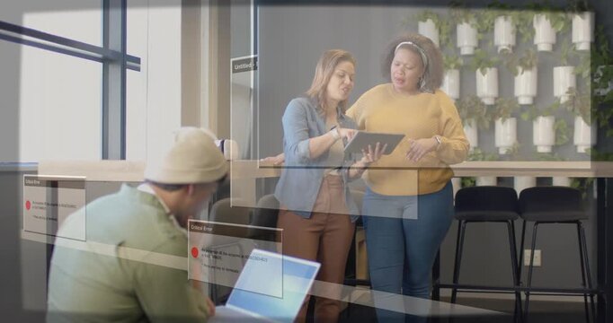 Two women tapping tablet, error overlays appearing over tech workspace, man typing laptop, fixing