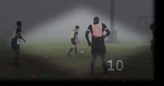 Male in orange bib standing, cone-grid passing starting soccer drill for ball control under light