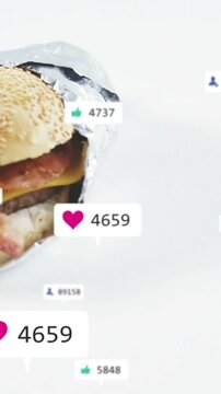 Vertical video: Wrapped sandwich while camera revealing heart and like counts rising for food ads