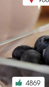 Vertical video: Ping icons popping in over blueberries in glass stacking counts and fading away