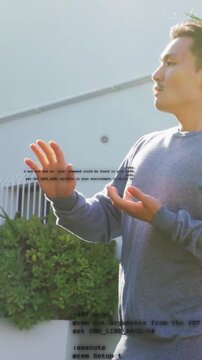 Vertical video: Male model standing by wall technology demo appearing opening hands extending arm