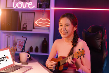 Host channel in musician of young beautiful Asian playing ukulele along singing, broadcasting on...
