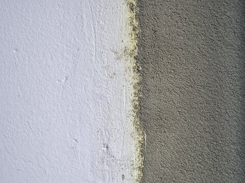 Close-Up of Wall Surface Showing Contrast Between Smooth White Paint and Rough Grey Cement Render &mdash; Renovation Before and After, Plastering, Construction and Wall Repair Concept