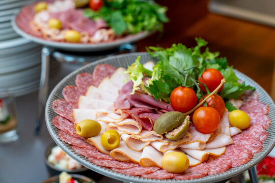 Assorted meat platter with sliced ham, salami, olives, and cherry tomatoes