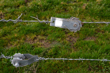 Tendeur crantés pour tendre une clôture dans un champ © luzulee