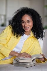 Naklejka premium Pretty curly-haired woman preparing for the exams and reading a book