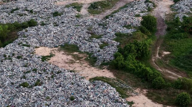 Large pile of garbage is on the ground. The pile is made up of many different types of trash