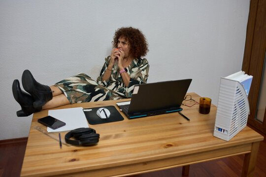 Businesswoman eating apple with feet up on desk at home
