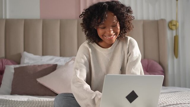 African American girl using laptop in bed at home office typing chatting reading writing email. Young black woman having virtual meeting online chat video call conference. Work learning from home