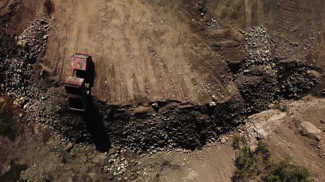 Aerial leveling scene with excavator smoothing ground filmed from above. Visible graded surface and blade marks with evened earth levels. Machinery creates flat pad for next construction phase.