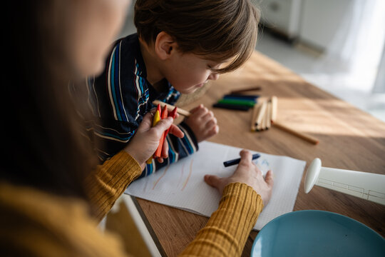 Mother and child drawing with crayons learning creativity