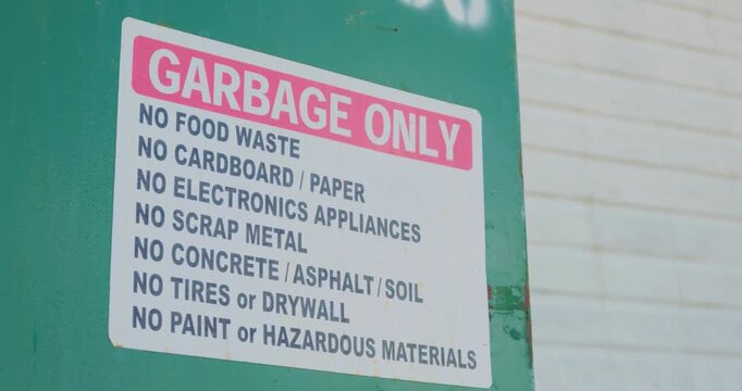 Close up of garbage only sign with prohibited waste list on bin