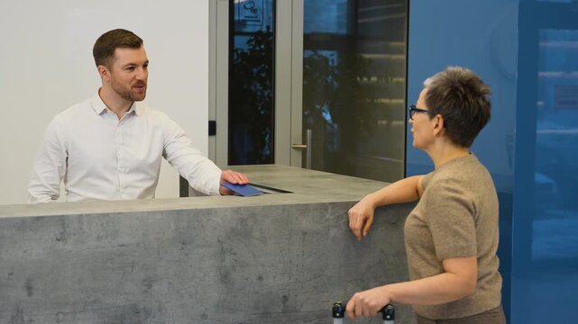 Female guest checking in at a modern hotel reception desk