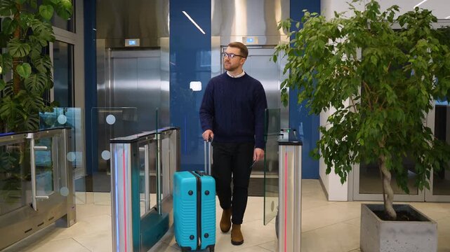 Businessman with suitcase passing through an electronic turnstile gate