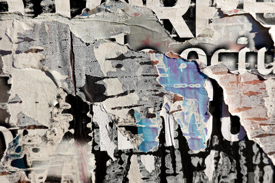 Old billboard with ripped torn posters background in city street