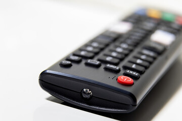 Obraz premium Remote control close up on white surface with power button focus