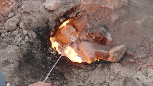 Close-Up of a Hand Roasting a Marshmallow Over the Eternal Flames at the Chimaera in Turkey, Natural Fire Emerging from the Rocky Ground, Unique Outdoor Cooking Experience