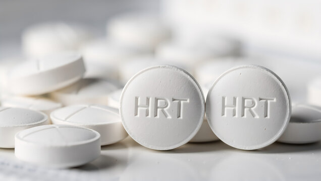 Close-up of white HRT pills for hormone replacement therapy. Medical treatment for menopause or gender transition. Pharmaceutical healthcare concept