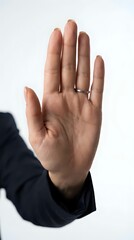 Obraz premium Open palm hand gesture showing stop sign with silver ring on finger against white background for communication and body language concepts.