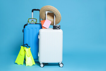 Suitcases, passports, hat, diving mask, camera and flippers on light blue background. Space for text © New Africa