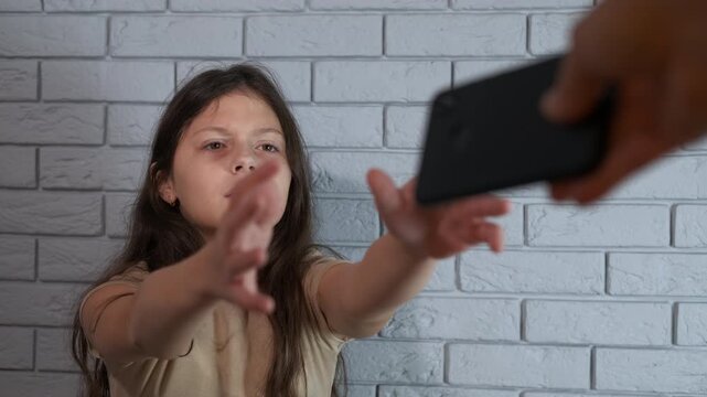 Teenage girl begging for her smartphone. Young girl with a desperate expression reaching for her smartphone, showing a strong dependence on technology and social media and illustrating a addiction