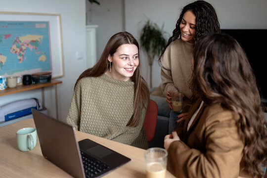 Happy friends having fun chatting around a laptop at home