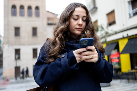Woman using smartphone on European street in winter