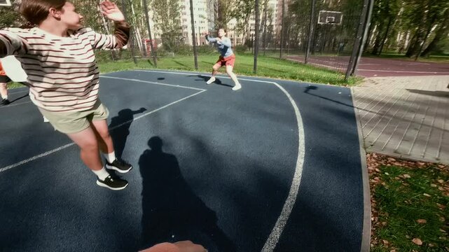 Action camera POV shot of unrecognizable teenage girl playing basketball game outdoors in urban street court with amateur all female team