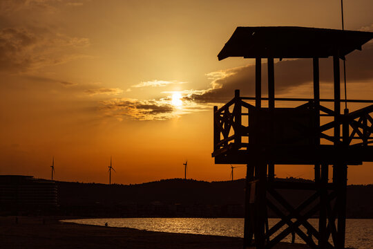 Lifeguard tower silhouette at golden sunset by the sea