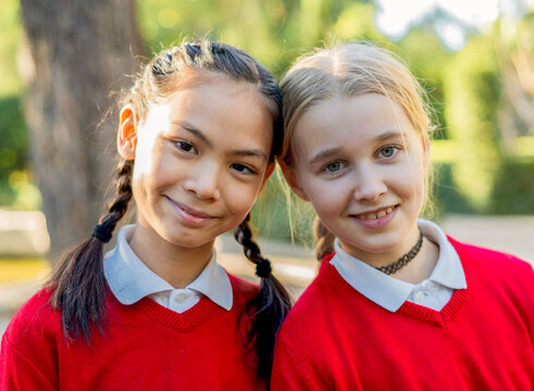 Two smiling girls in red sweaters enjoying outdoor time