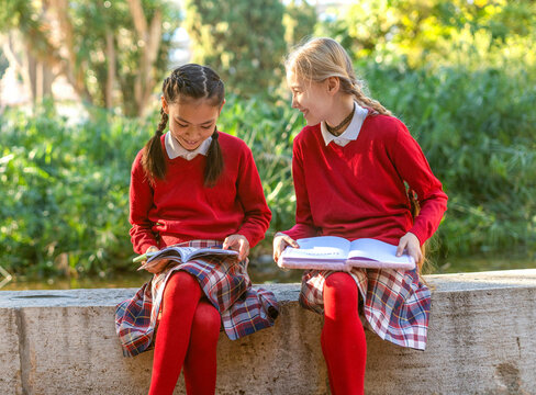 Two young girls enjoying reading books outdoors