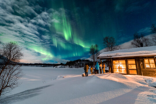 Northern lights over cabin and tourists in Tromso, Norway