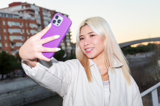Urban Gen Z girl taking a smartphone selfie at sunset