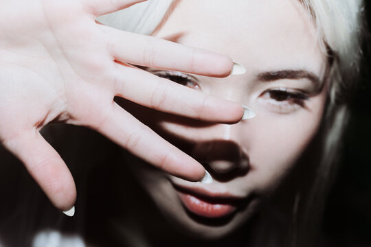 Gen Z girl shielding face from flash in moody closeup