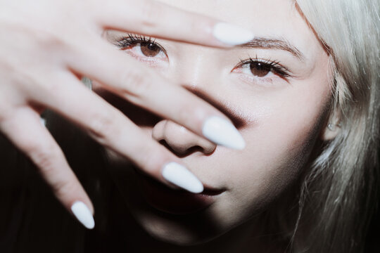 Gen Z girl shielding face from flash in moody closeup