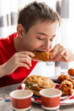 Boy eating chicken wing with burger at USA 4th of July party