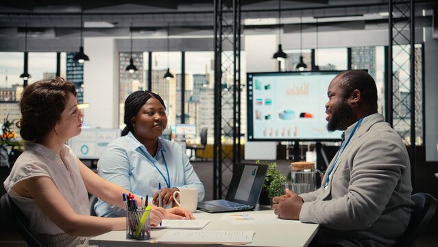 Black job seeker sitting across from human resources team during hiring process discussion, presenting work experience and qualifications for business organization job offer. Career goals. Camera A.