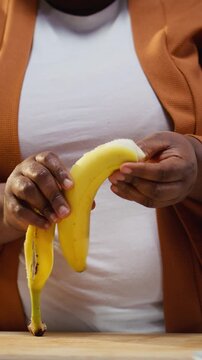 Content creator pealing a banana and adding slices on chia bowl, preparing a healthy breakfast meal for online audience. Woman filming meal prep with fruits and yogurt, chia pudding.
