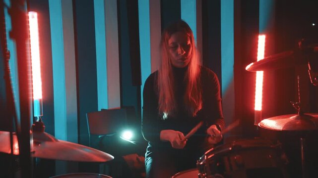Professional woman drummer playing drums in music studio