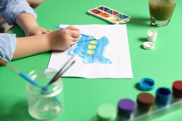 Little girl painting picture with paints and brush on green background, closeup © New Africa