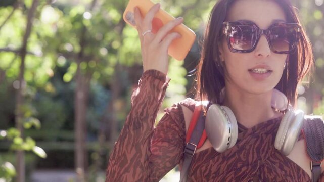 Happy young student dancing with smartphone in a public park