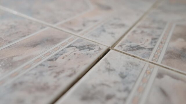 Loose Floor Tile Inspection Close-Up: Tiler Pressing Uneven Ceramic Tile That Moves and Lifts Above Floor Level | Home Repair and Maintenance Concept