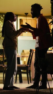 Vertical Video Black couple fighting at home in dark hallway looking furious and enraged during domestic quarrel. Unhappy partners in conflict, toxic relationship due to constant heated argument and