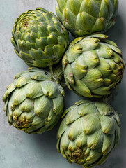 Fototapeta premium Fresh green artichokes arranged closely on a textured surface showcasing their layered leaves and natural earthy colors for healthy cooking ideas