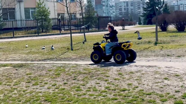 Child riding a small electric quad bike outdoors. Active play, kids vehicle, outdoor activity and fun childhood lifestyle in an urban park setting