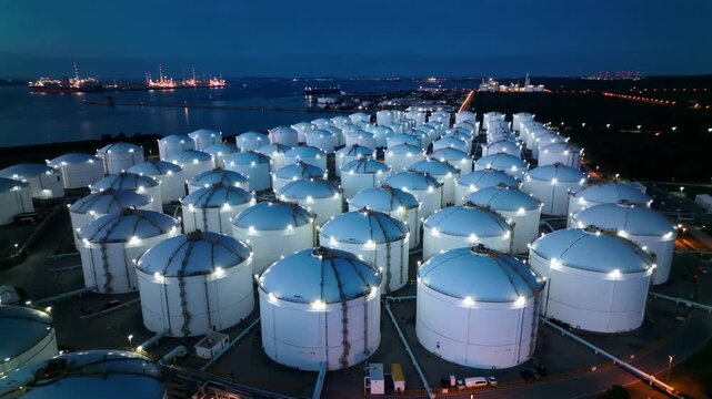 Oil storage tanks at industrial refinery terminal at night aerial view