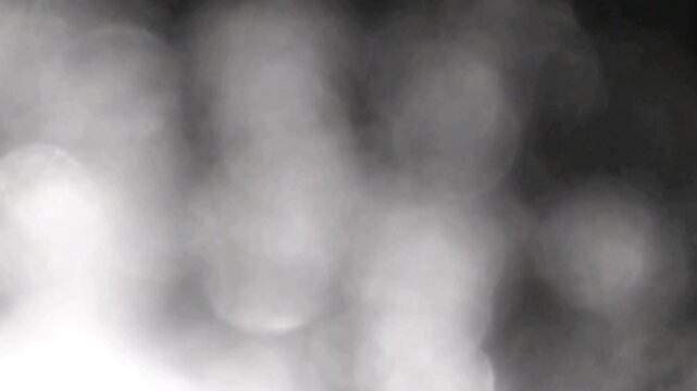 Monochromatic soft bokeh spheres shift gently in a blurry silver and gray out of focus background loop.